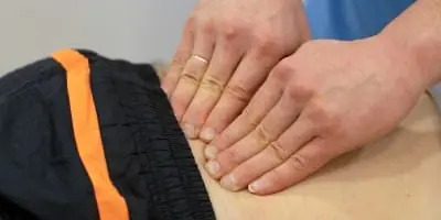 Terapeut undersöker ryggraden med händerna under en osteopatisk behandling